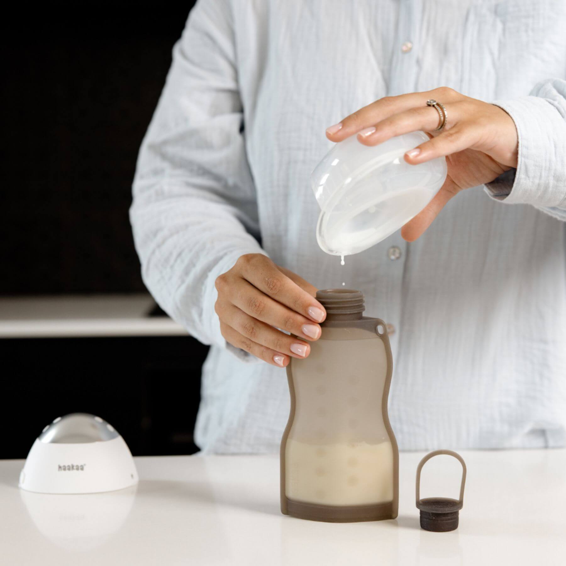 Person pouring liquid into a brown bottle with a white background