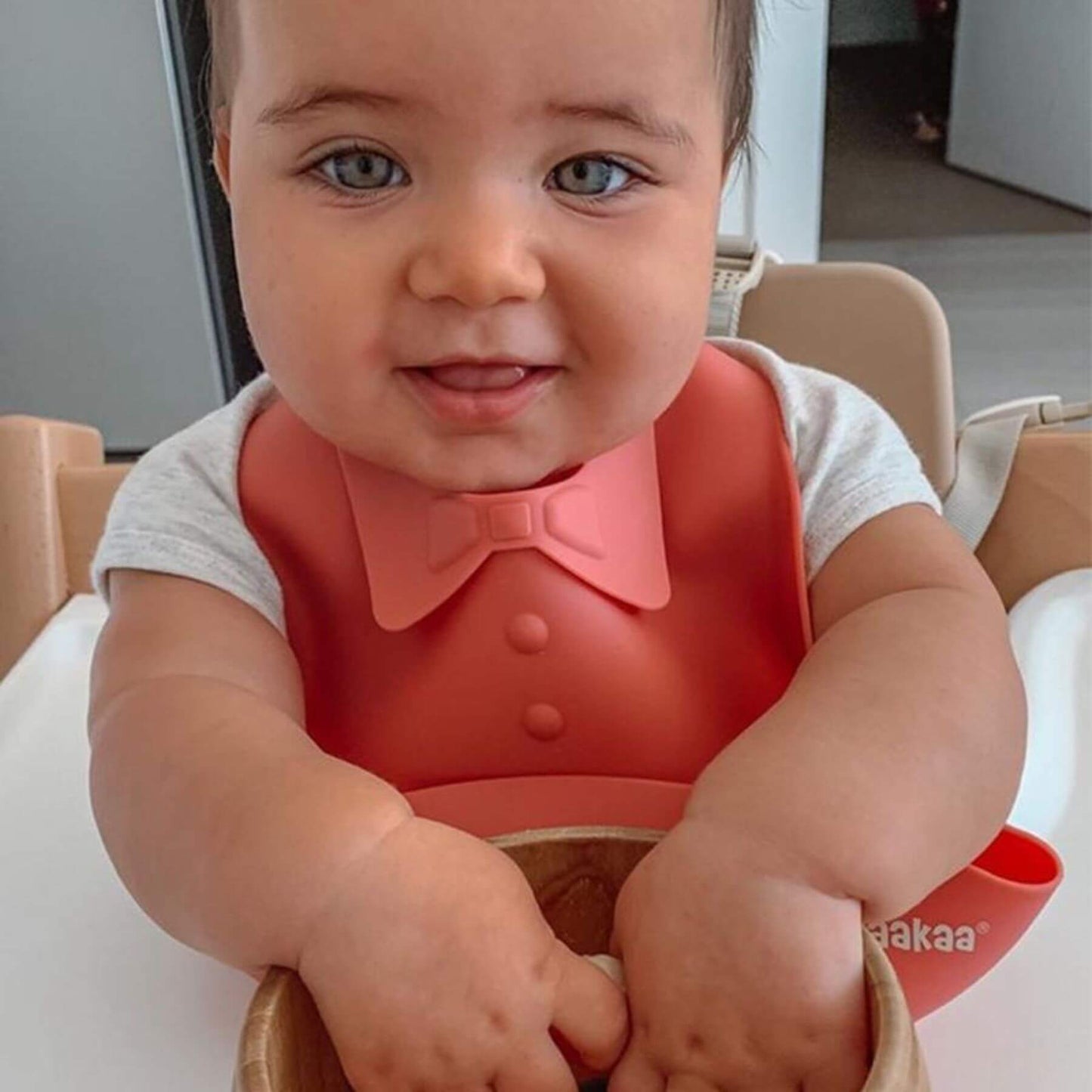 Child wearing a red bib with a bow tie, sitting in a high chair.