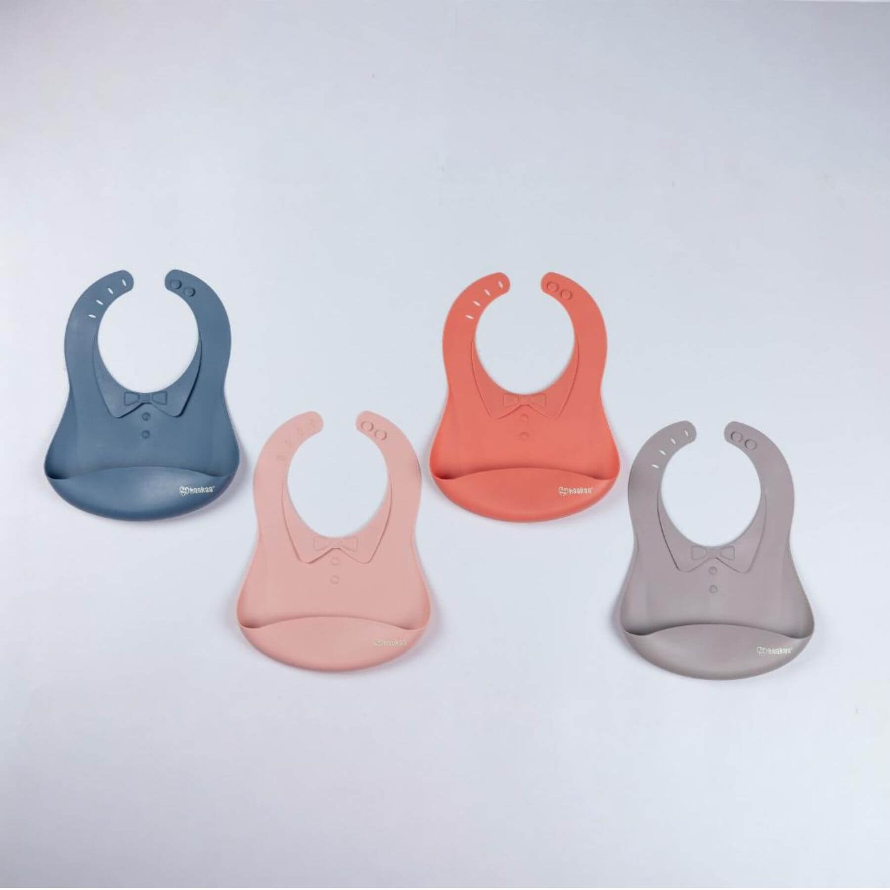 Four silicone bibs in blue, pink, and gray on a light gray background