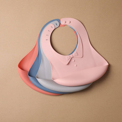 Stack of pink, blue, and gray baby bibs on a beige background