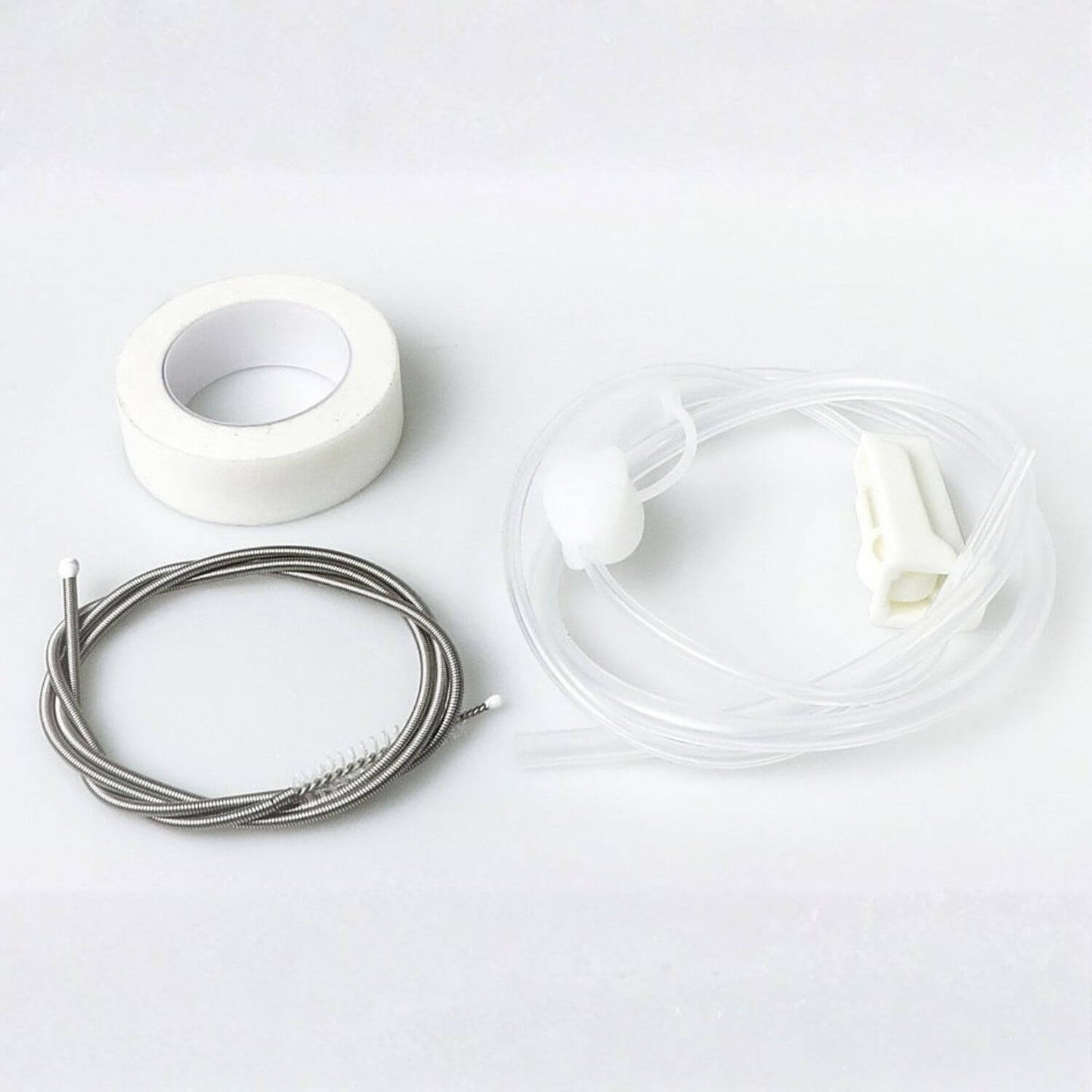 A cleaning kit containing a roll of white tape, a coiled stainless steel wire brush, and clear plastic tubing with white plastic connectors, laid out on a white background.