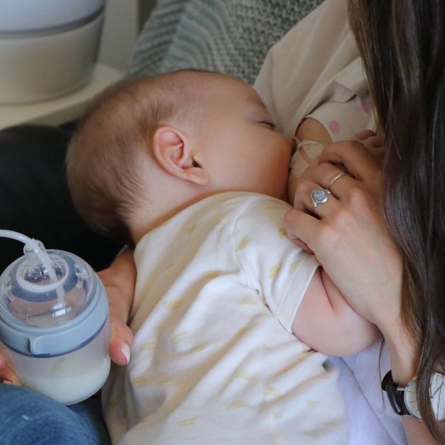 Baby being held by a person with a bottle in the foreground