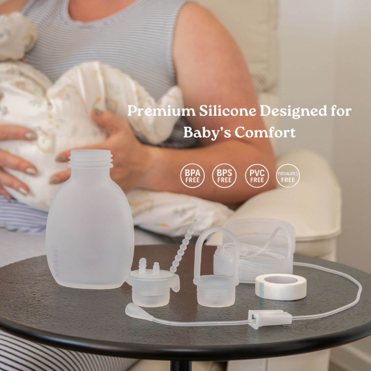 Haakaa Supplemental Feeding Tube & Pouch Set on a table with text 'Premium Silicone Designed for Baby's Comfort' and safe material icons.