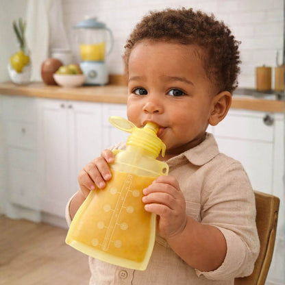 Child drinking from a yellow pouch in a kitchen setting