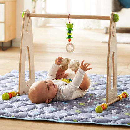 Baby playing with HABA USA Color Fun Play Gym Activity Center on a mat.