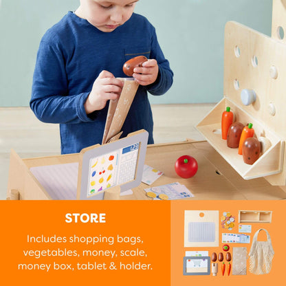 Child playing with a wooden toy set including vegetables, money, and a scale.