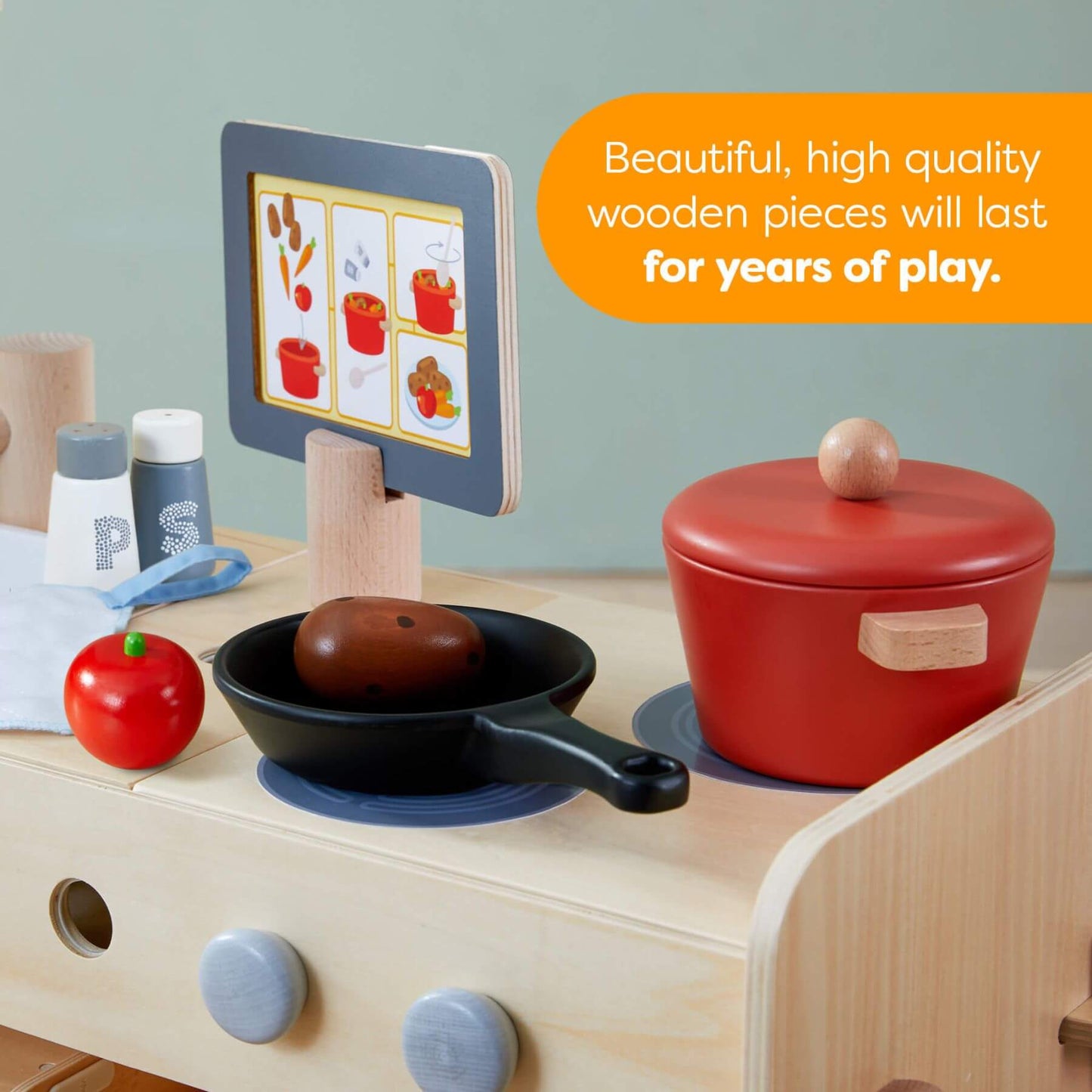Wooden play kitchen set with toy food and cookware on a light blue background.