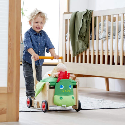 Child pushing HABA USA Dragon Wagon Baby Walker in a bedroom setting.