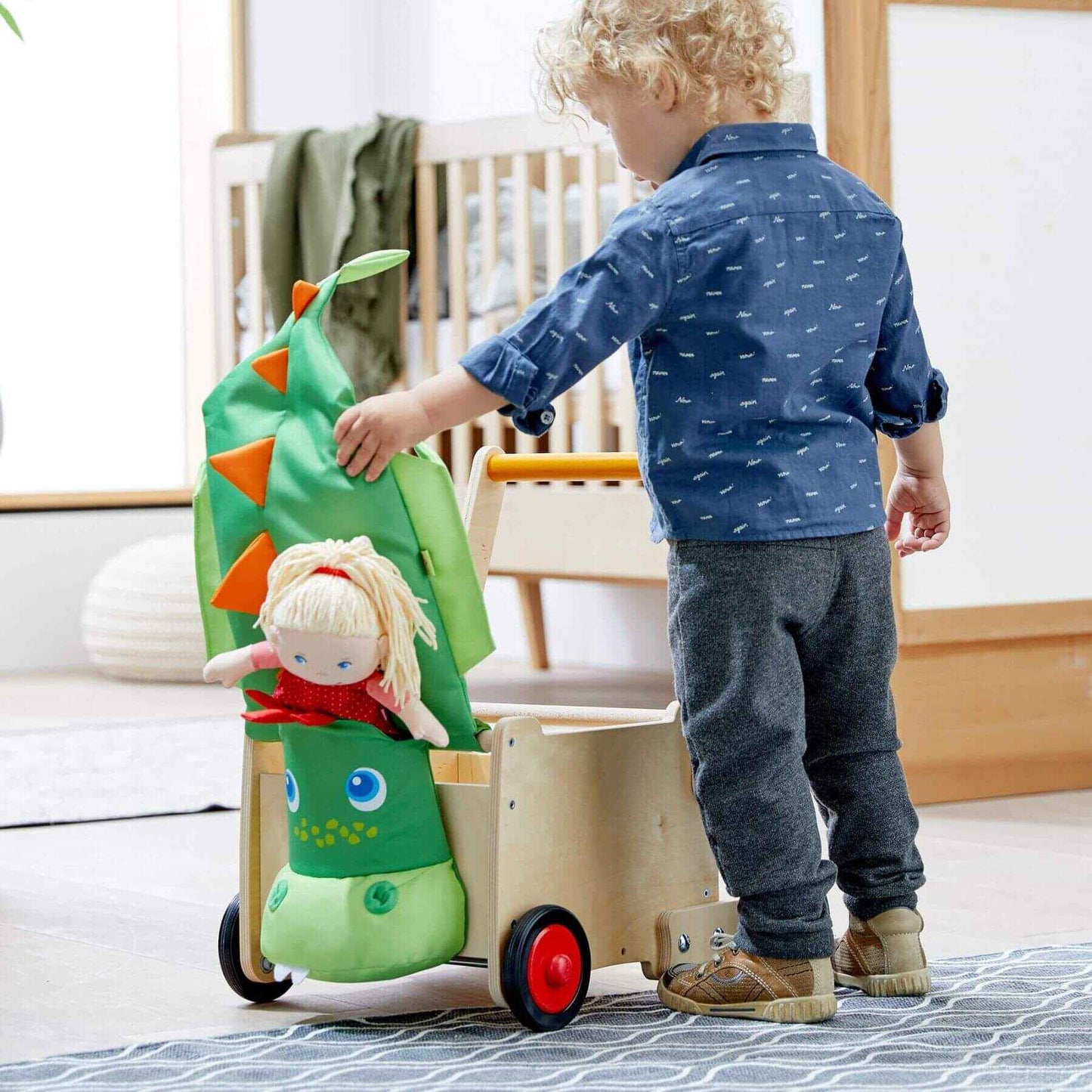 Child playing with HABA USA Dragon Wagon Baby Walker in a room.