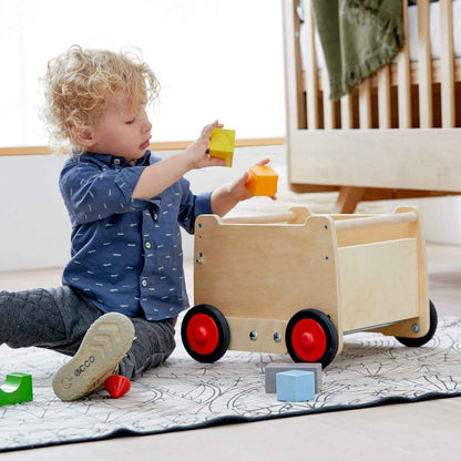 Child playing with HABA USA Dragon Wagon Baby Walker on a light-colored floor.