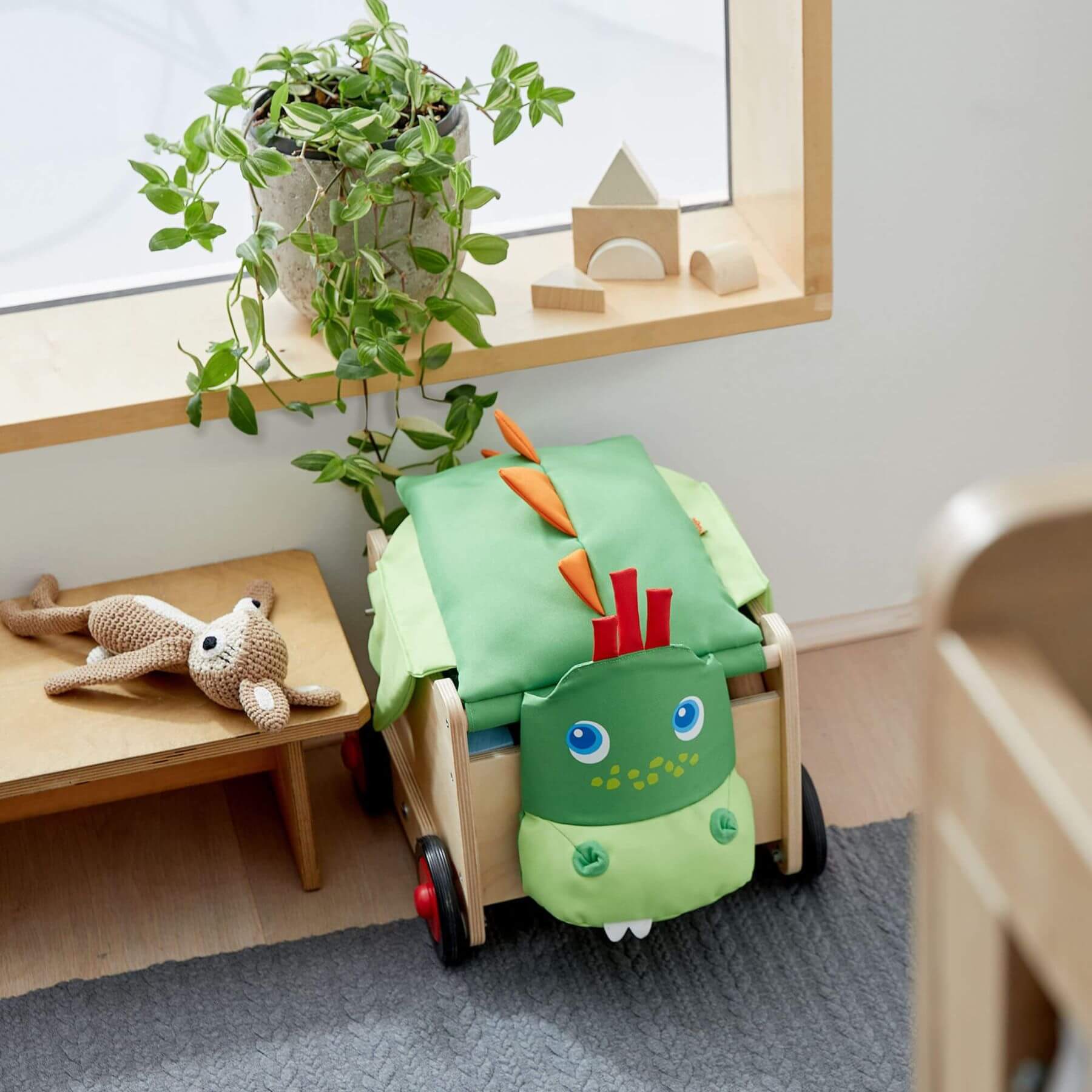 Children's room with HABA USA Dragon Wagon Baby Walker, plant, and toys.
