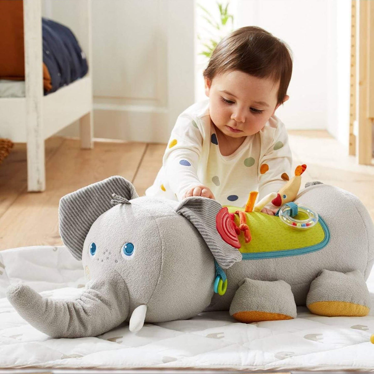 Child playing with HABA USA Elephant Discovery Pillow on a bed