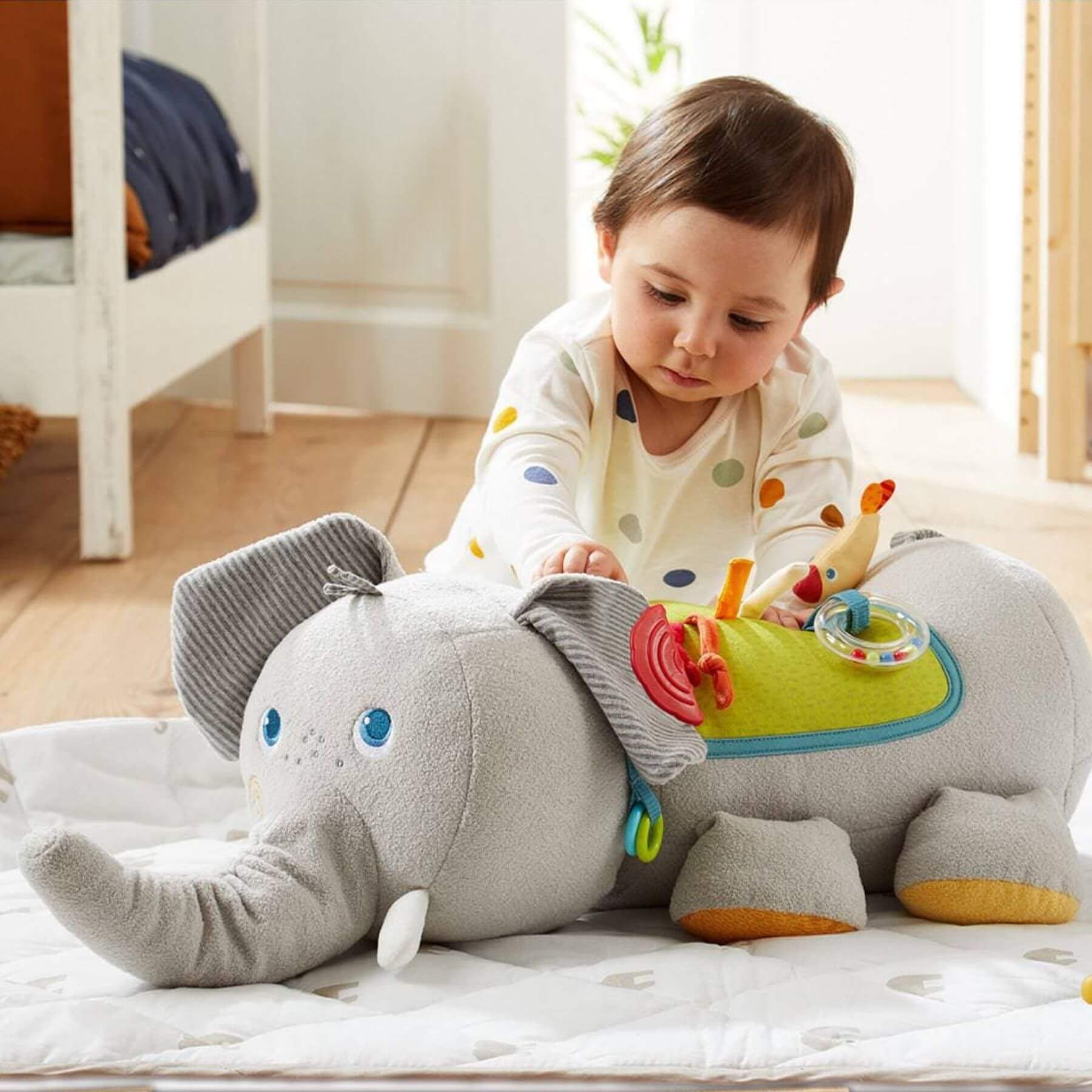 Child playing with HABA USA Elephant Discovery Pillow on a bed