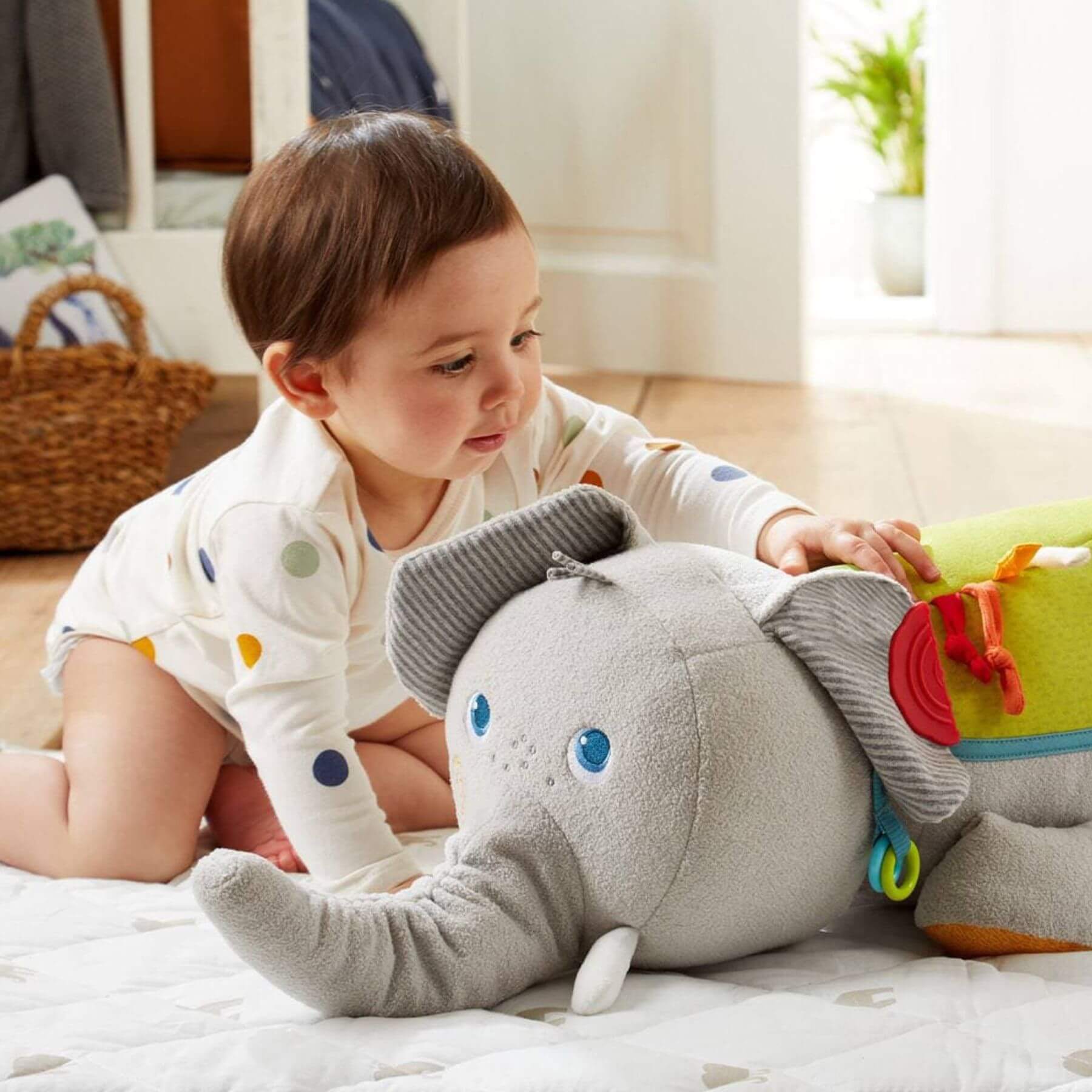 Baby playing with HABA USA Elephant Discovery Pillow on a bed