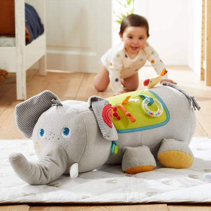 Child playing with HABA USA Elephant Discovery Pillow on a bed