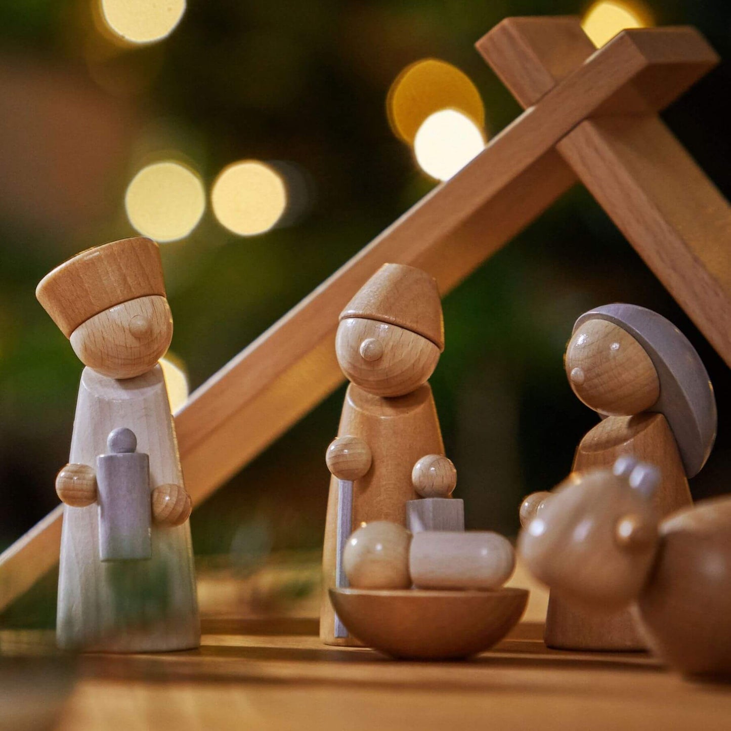 Wooden nativity scene with three figures against a blurred light background