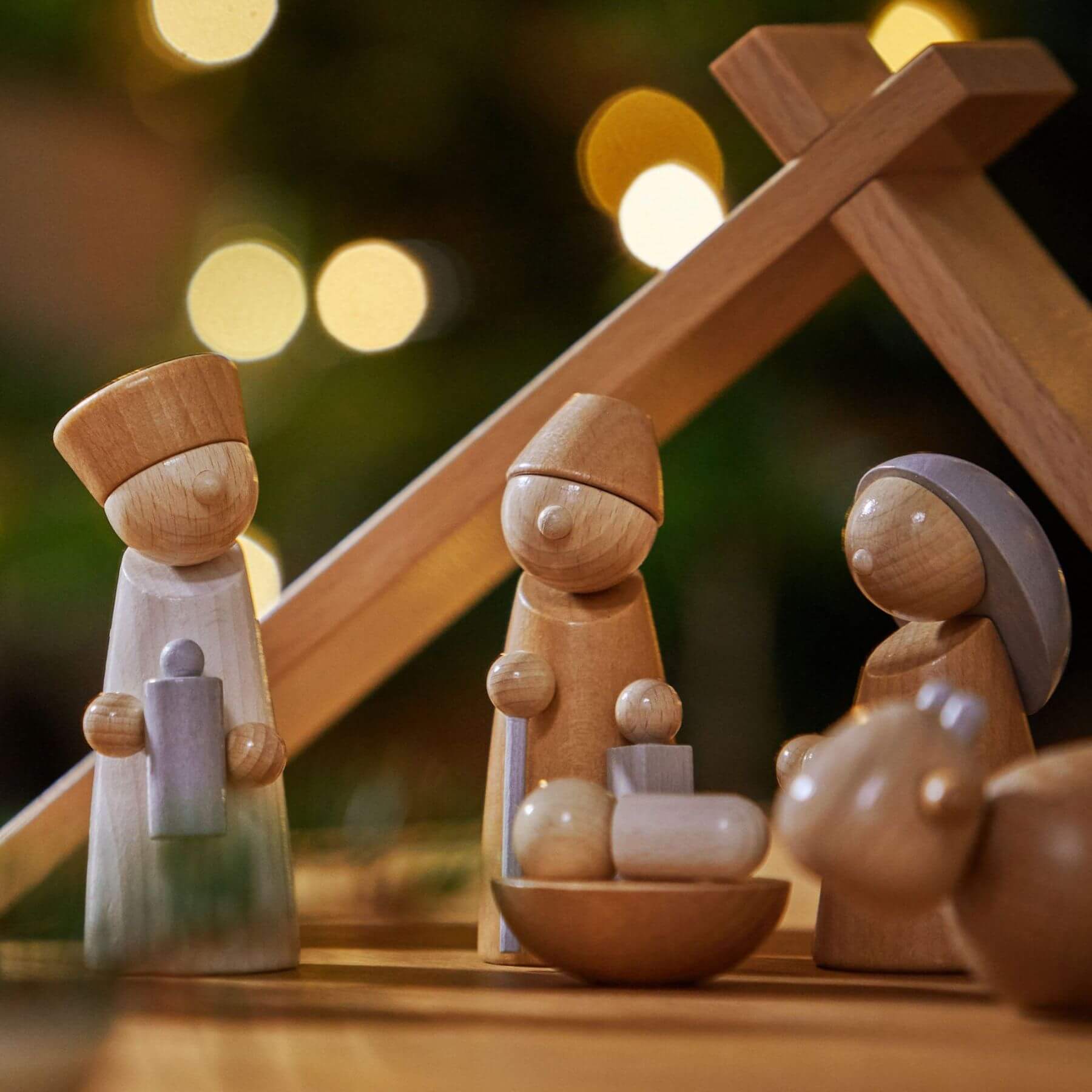 Wooden nativity scene with three figures against a blurred light background
