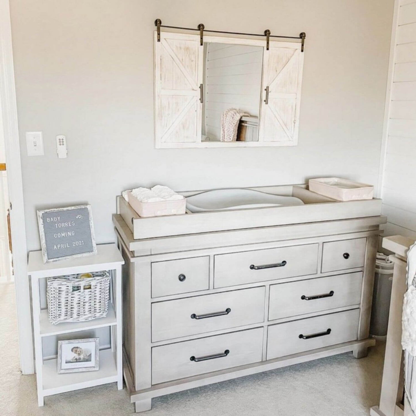 Nursery with changing table, mirror, and side table.