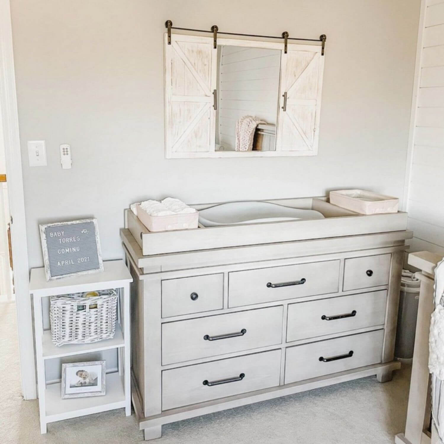 Nursery with changing table, mirror, and side table.