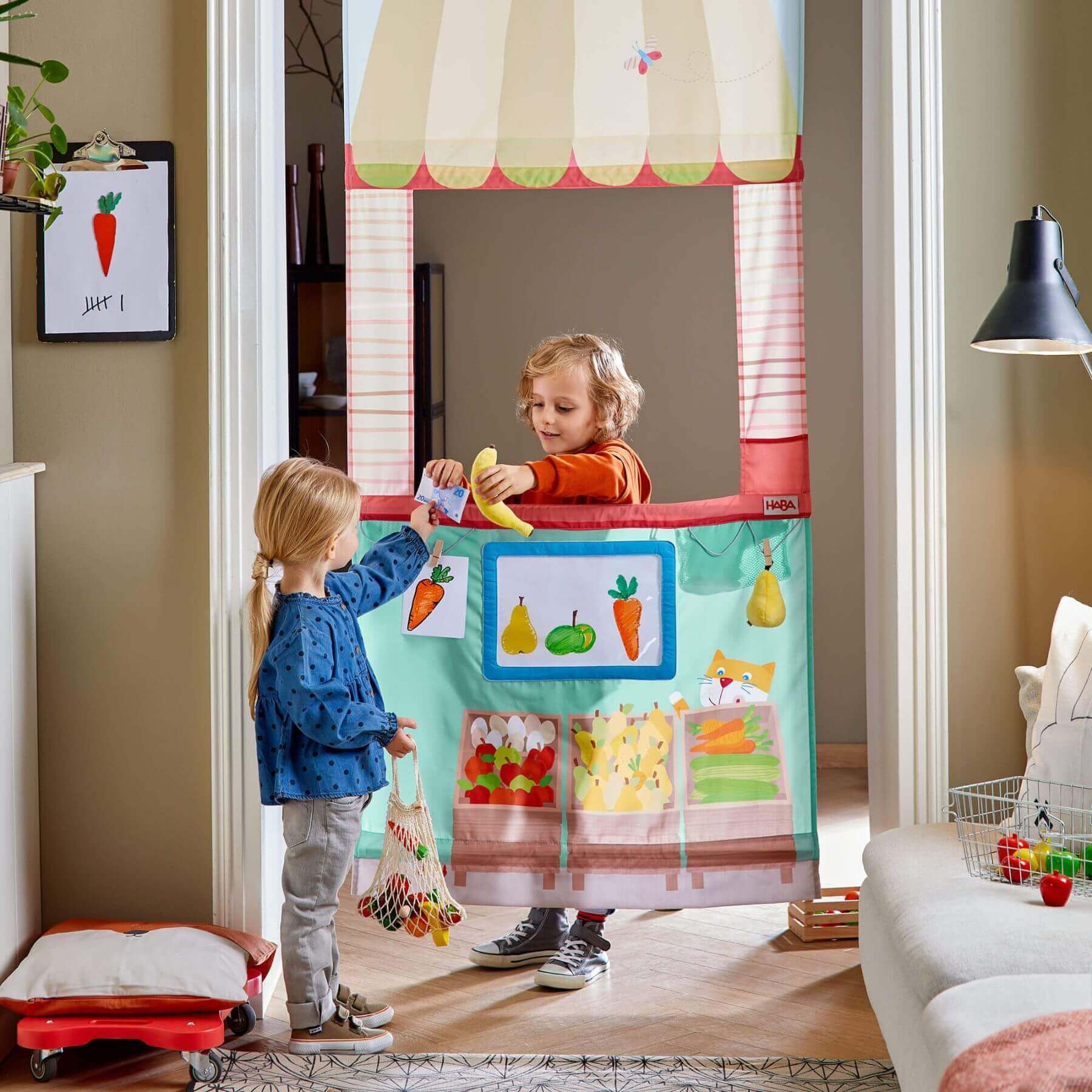 Two children playing with HABA USA Hanging Doorway Play Store in a living room.