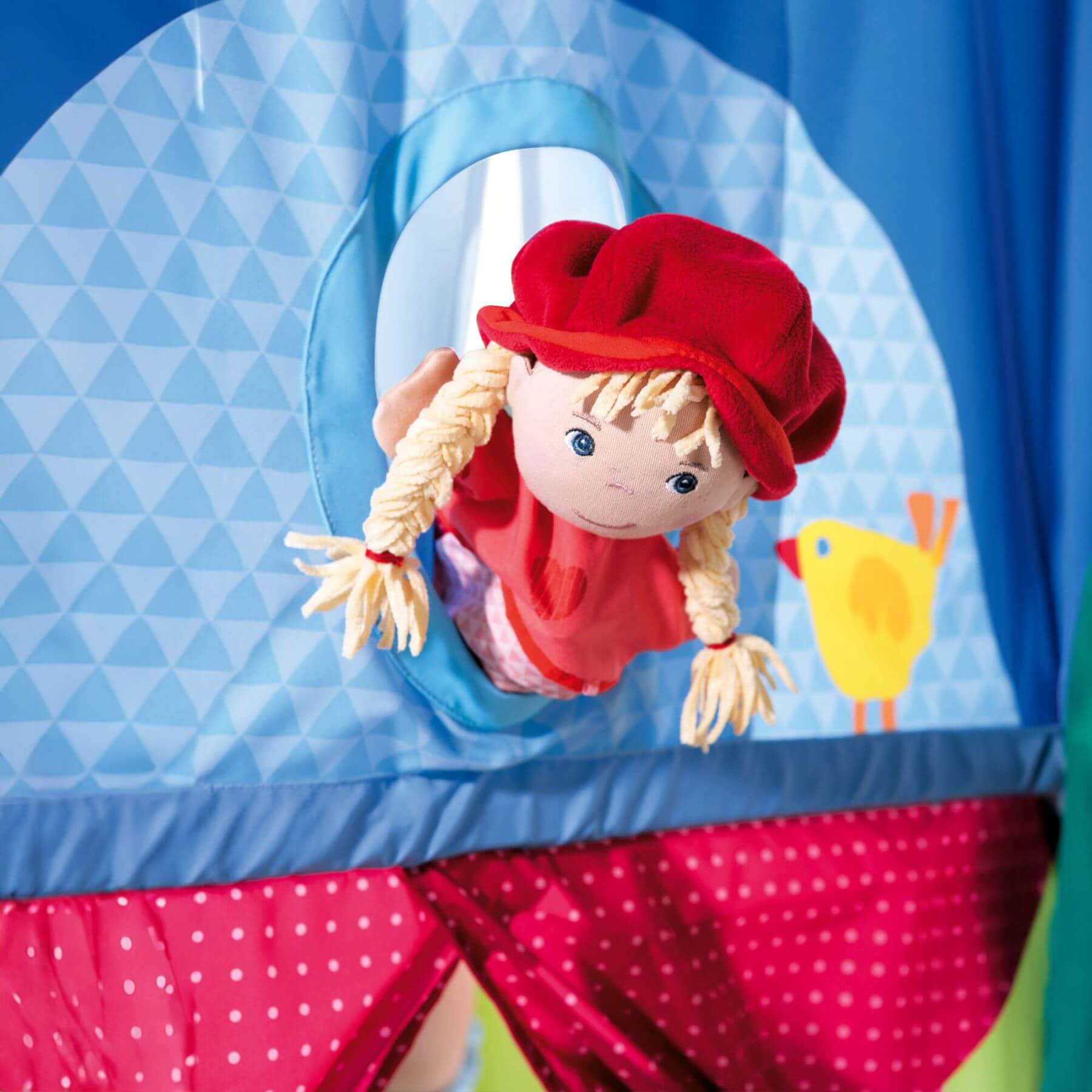 Toy character with a red hat and dress inside HABA USA Hanging Doorway Puppet Theater