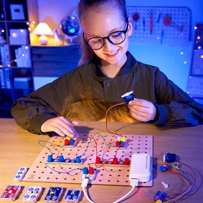 A girl is playing Hape Lab Box Circuit Explorer Boost at a desk