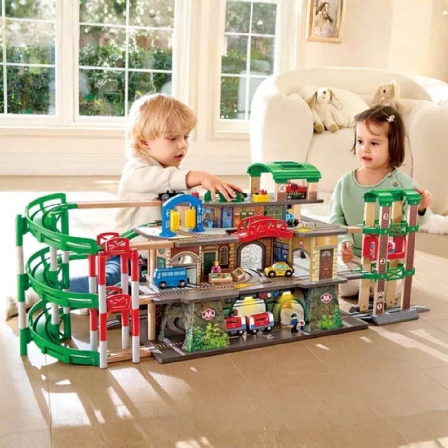 Two kids playing with Hape Multi-Level Railway City Set in a living room