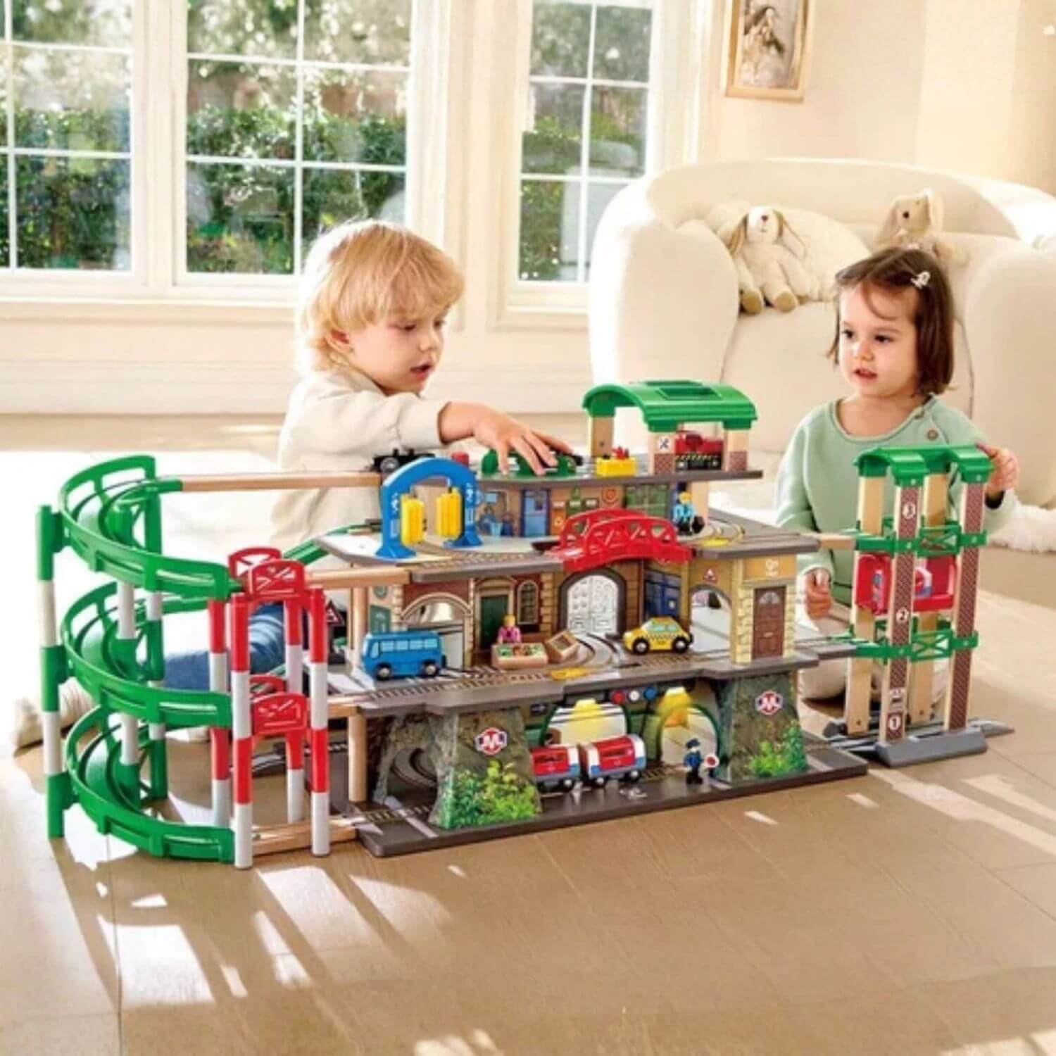 Two kids playing with Hape Multi-Level Railway City Set in a living room