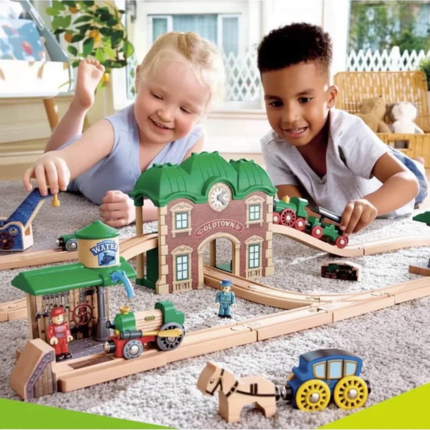 Two children playing with Hape Wooden Retro Train & Station Set on a carpeted floor.