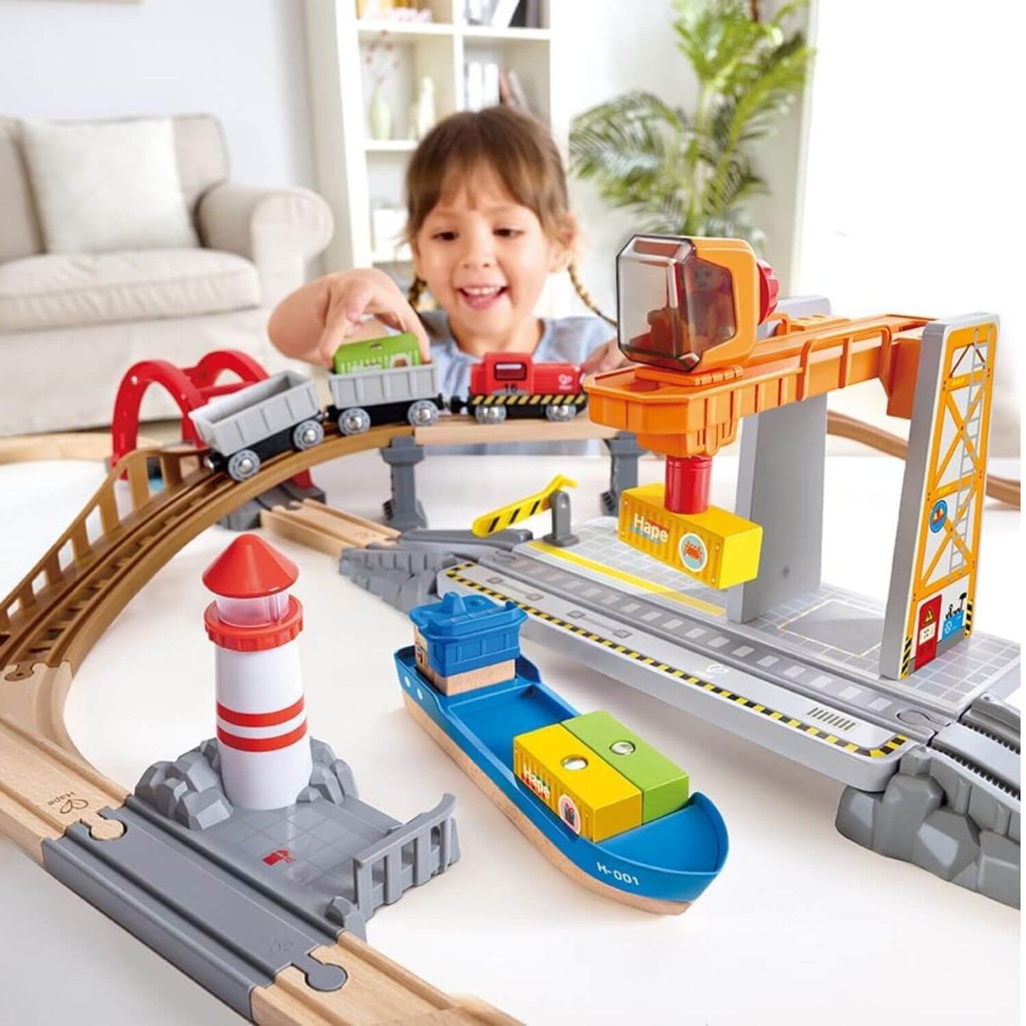 Girl playing with Hape Sea & Rail Cargo Transportation Set on floor