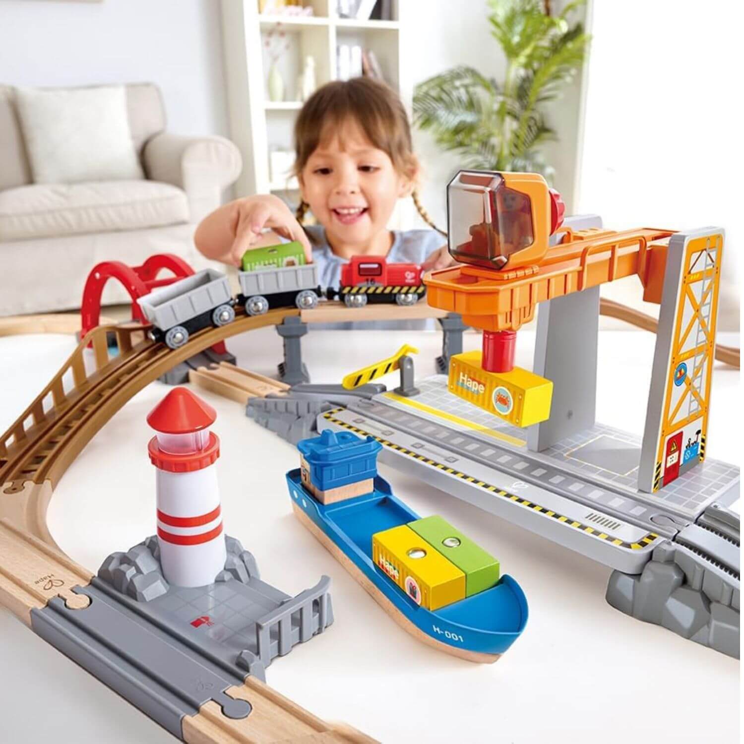 Girl playing with Hape Sea & Rail Cargo Transportation Set on floor