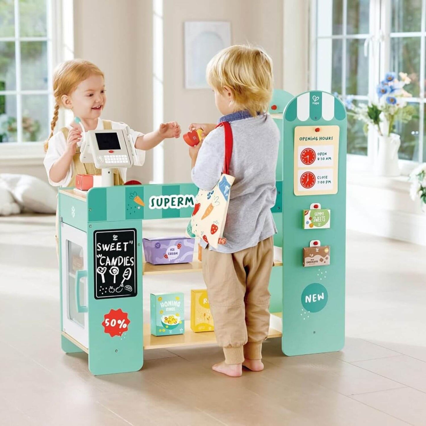 Two children playing with Hape Smart & Wooden Supermarket in a bright room.
