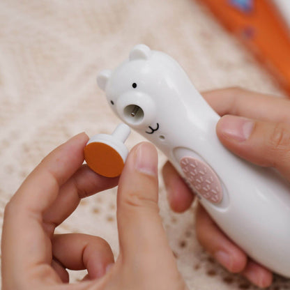 Haakaa Happii Bear Rechargeable Nail Trimmer held by hands on a beige background