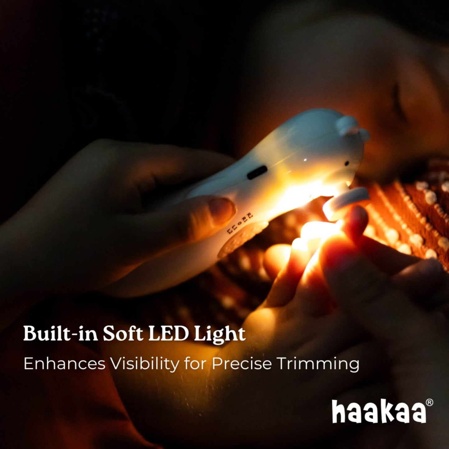 Person holding a haakaa nail trimmer with a built-in soft LED light in a dark setting.