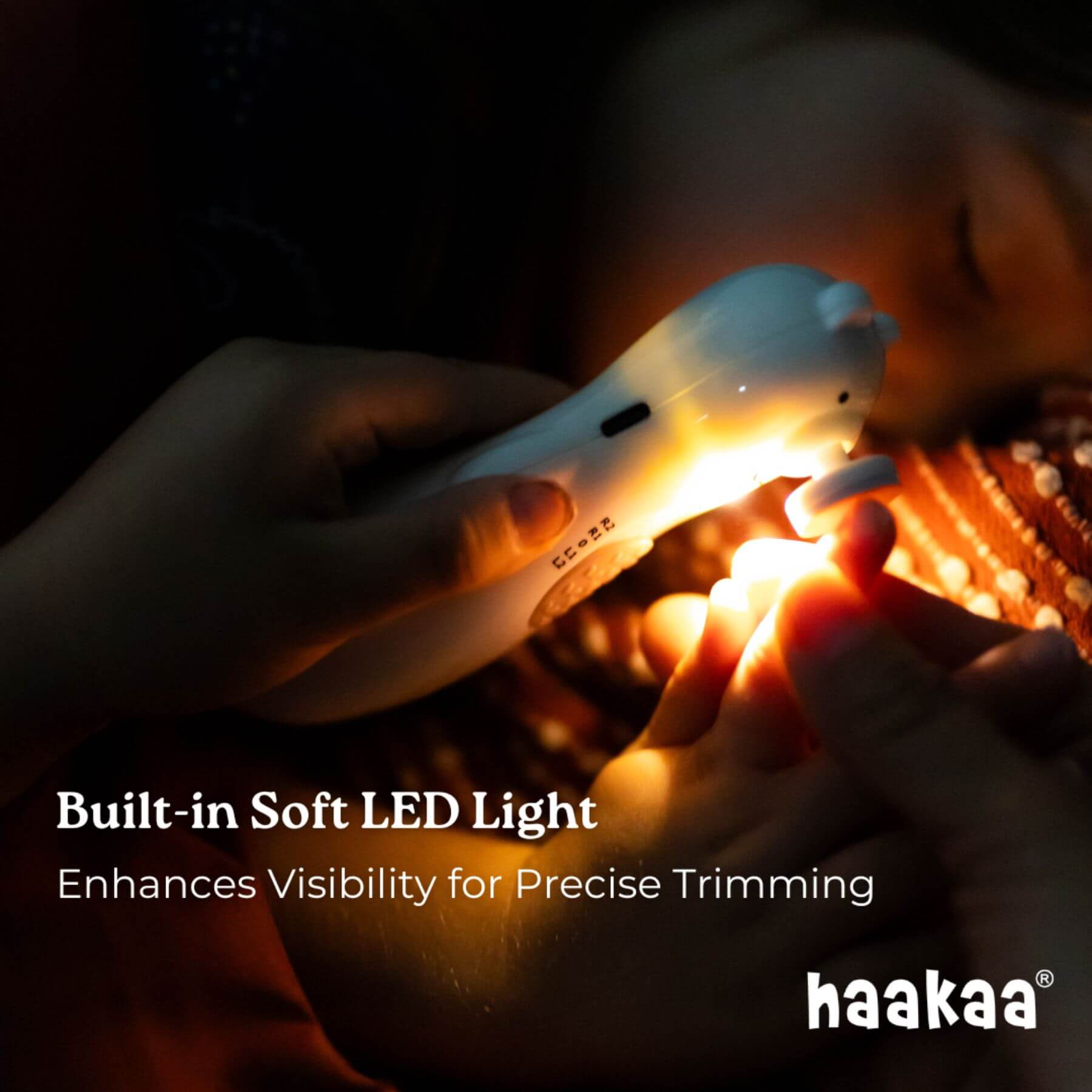 Person holding a haakaa nail trimmer with a built-in soft LED light in a dark setting.