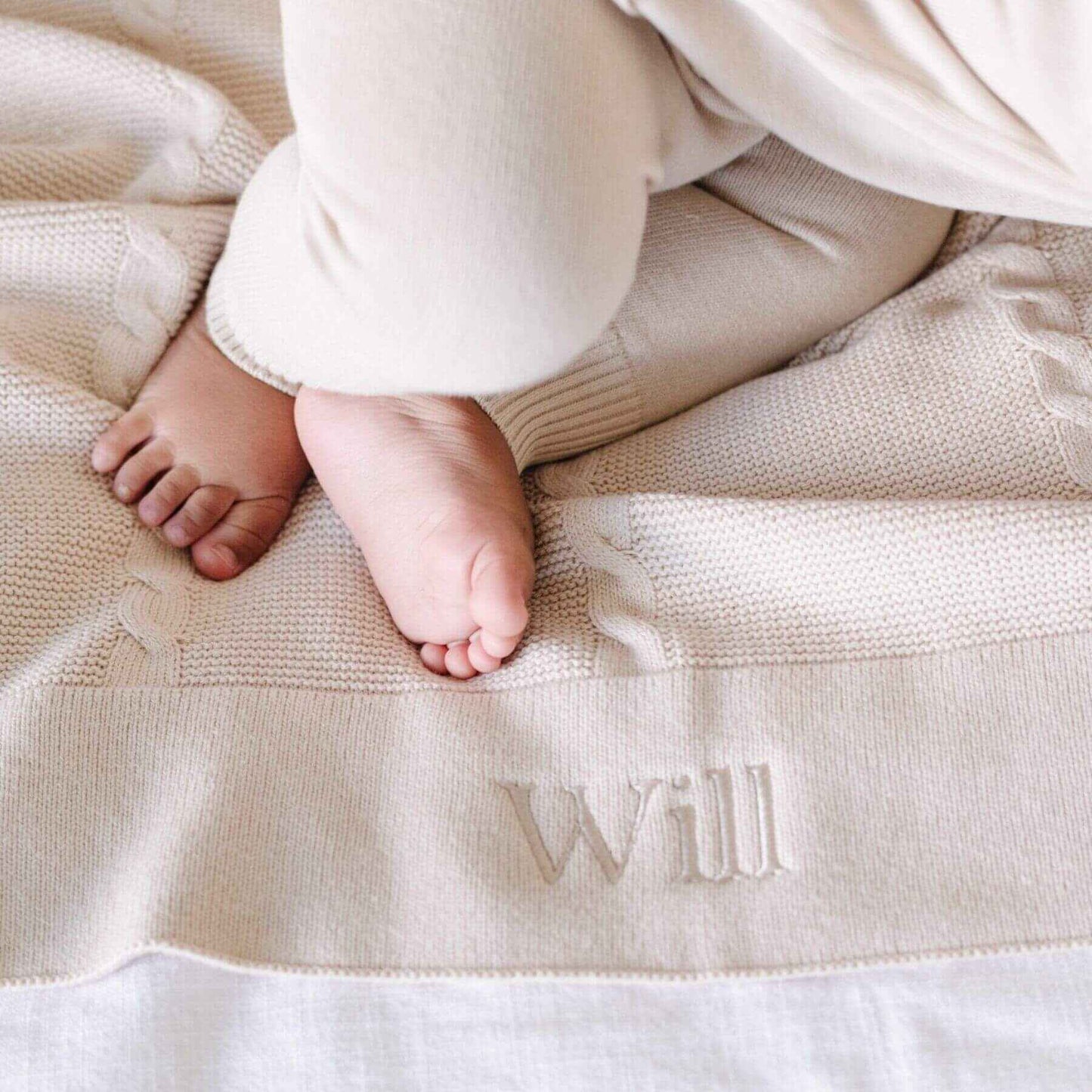 Baby feet on Saranoni Heirloom Cotton Knit Receiving Blanket with 'Will' embroidered on it