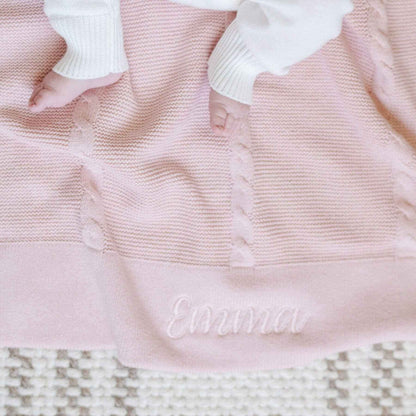 Close-up of Saranoni Heirloom Cotton Knit Receiving Blanket with 'Emma' embroidered on it, on a checkered surface.