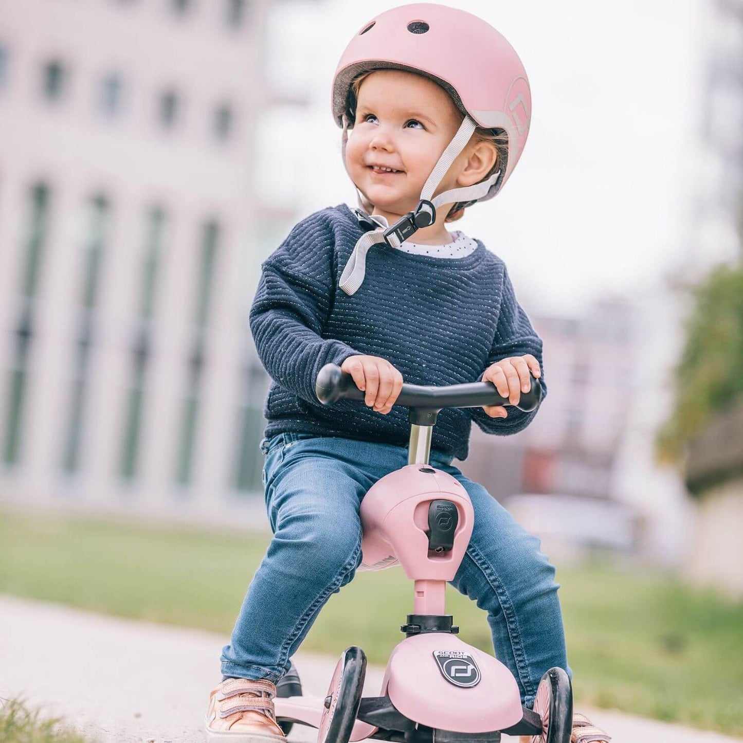 Child riding HighwayKick 1 Scooter and Ride On Toy Rose with a helmet outdoors