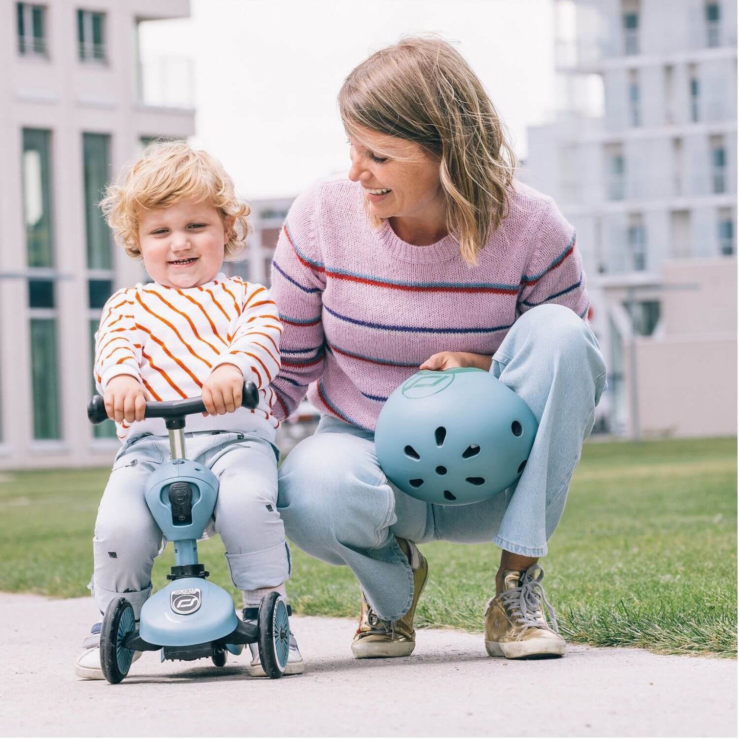 Woman and child with a blue scooter in an outdoor setting