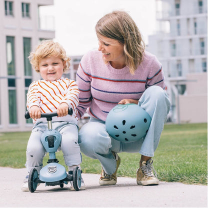 Woman and child with a blue scooter in an outdoor setting
