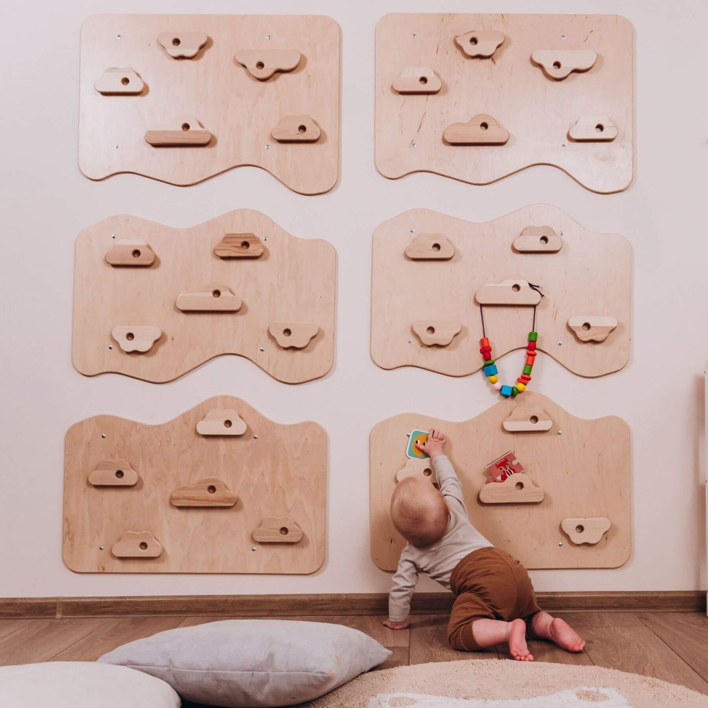 Child playing with a colorful toy on a wooden climbing wall panel in a room.