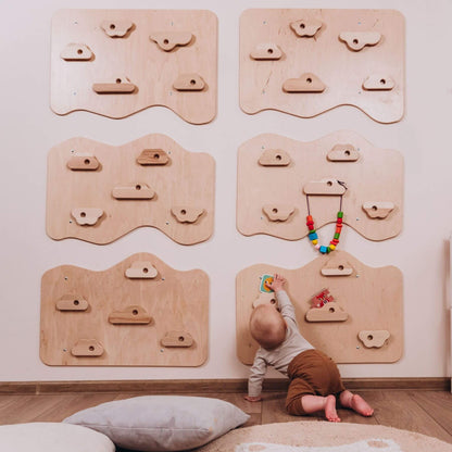 Child playing with a colorful toy on a wooden climbing wall panel in a room.