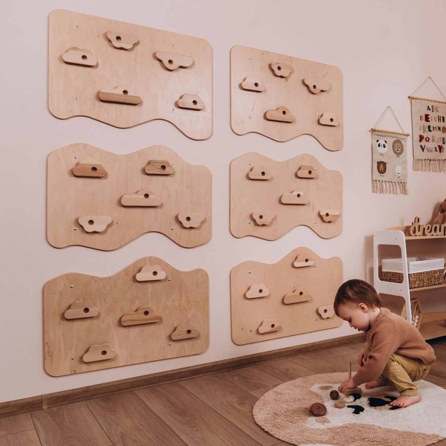 Child playing on a rug with wooden climbing structures on the wall