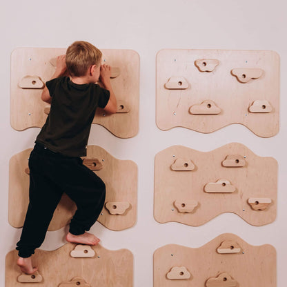Child climbing on a wooden climbing wall with various holds against a white background