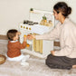 Woman and child playing with Tiny Land® Honey Kitchenette - Little Chef's First Kitchen on a carpeted floor.