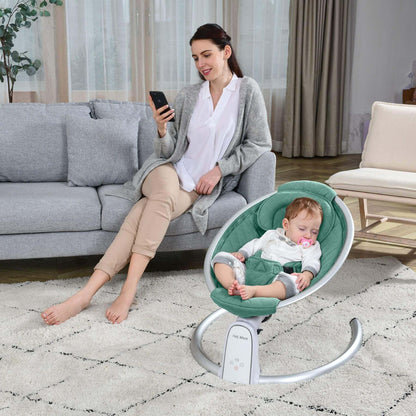 Woman sitting on a couch using a phone with a baby in Hot Mom Electric Baby Bouncer for Infant - Green on a rug.