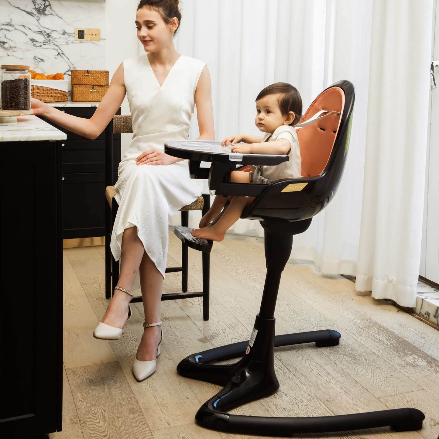 Woman in a white dress sitting at a desk with a child in Hot Mom High Chair - Black Gold
