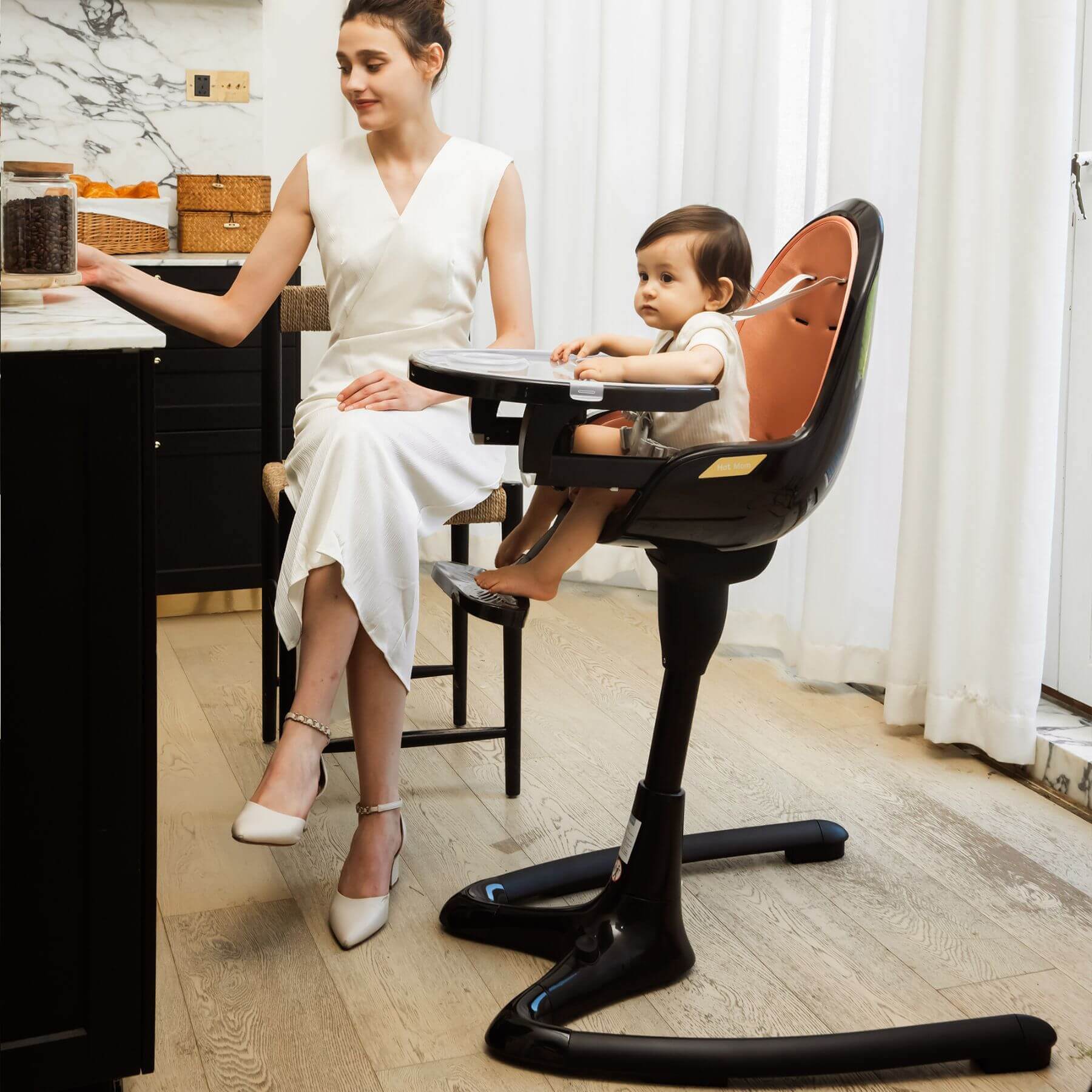 Woman in a white dress sitting at a desk with a child in Hot Mom High Chair - Black Gold