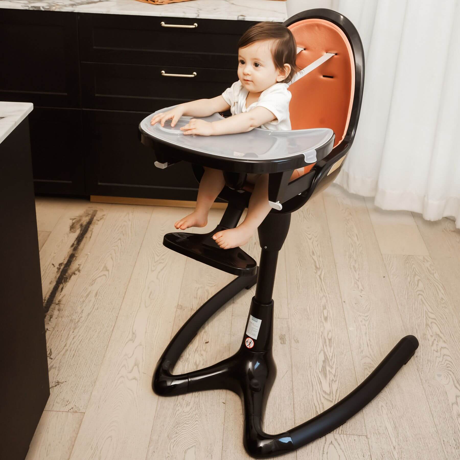 Child sitting in Hot Mom High Chair - Black Gold in a kitchen setting