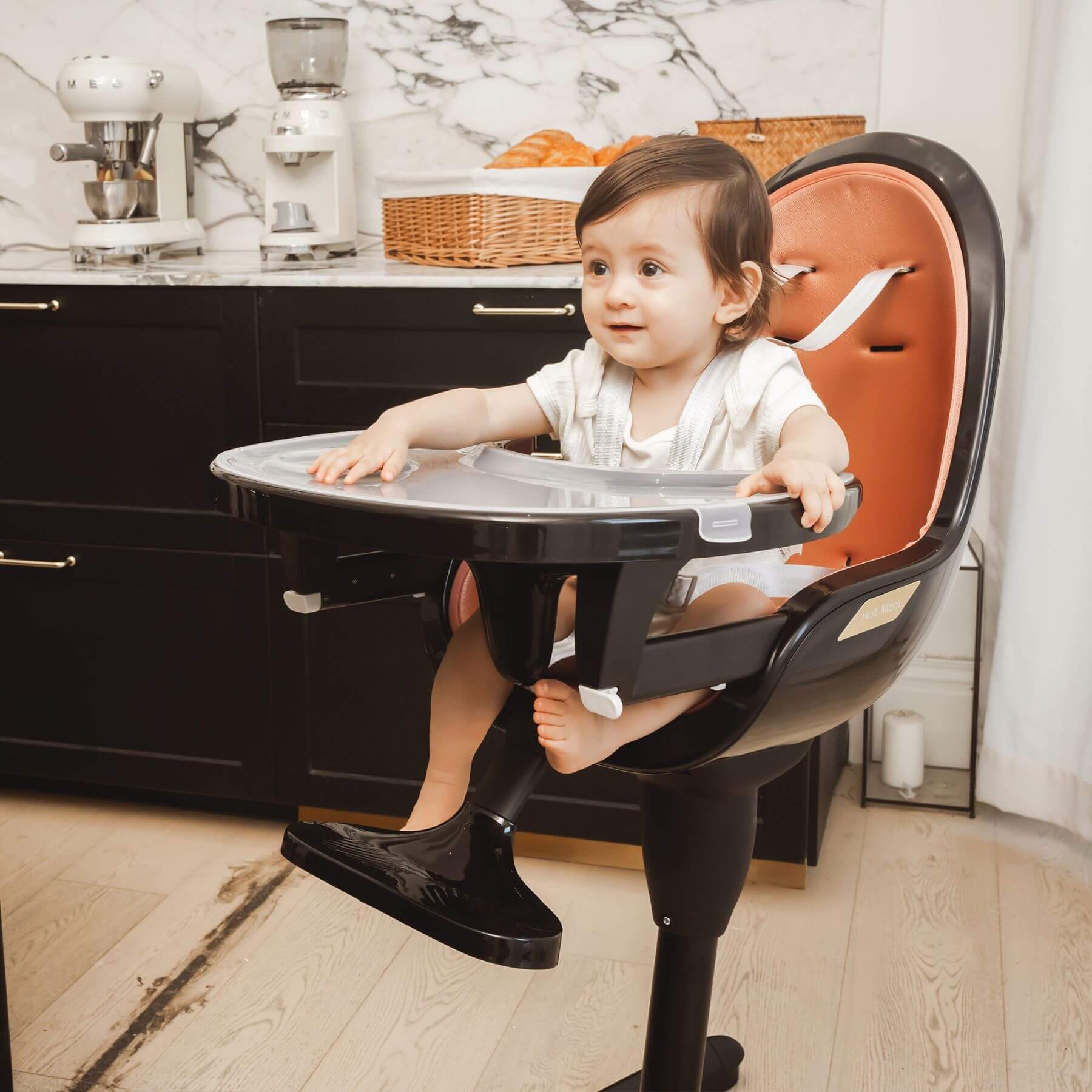 Child sitting in Hot Mom High Chair - Black Gold in a kitchen